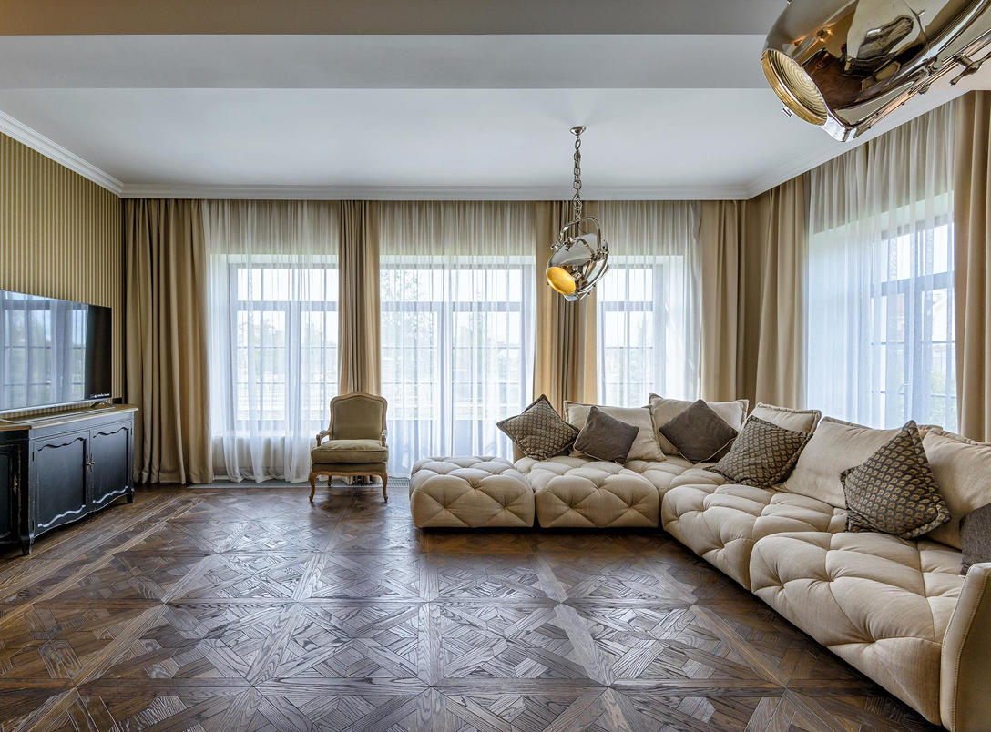 Same living room fully renovated, with hardwood flooring, curtains, and furnished seating